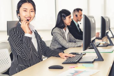 Ofiste çalışan kulaklık takan işadamları uzak müşteri ya da meslektaşlarını desteklemek için çalışıyorlar. Arama merkezi, tele pazarlama, müşteri destek acentesi telefon görüşmesinde hizmet sunar.