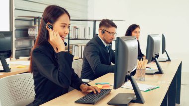 Ofiste çalışan kulaklık takan işadamları uzak müşteri ya da meslektaşlarını desteklemek için çalışıyorlar. Arama merkezi, tele pazarlama, müşteri destek acentesi telefon görüşmesinde hizmet sunar.
