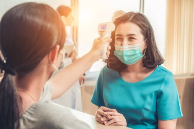 Ofiste ya da hastanede konuşurken resepsiyonist ve misafir maske takıyor. Covid 19 ve Coronavirus enfeksiyon koruması ve koruma politikası kavramı .