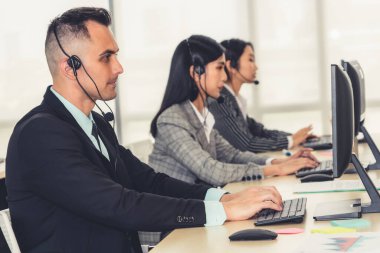 Ofiste çalışan kulaklık takan işadamları uzak müşteri ya da meslektaşlarını desteklemek için çalışıyorlar. Arama merkezi, tele pazarlama, müşteri destek acentesi telefon görüşmesinde hizmet sunar.