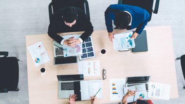 İş adamları grup toplantısı ofiste yukarıdan çekildi. İş kadınları, iş adamları ve ofis çalışanları, proje planlama belgeleriyle takım konferansında toplantı masasında çalışıyorlar. .
