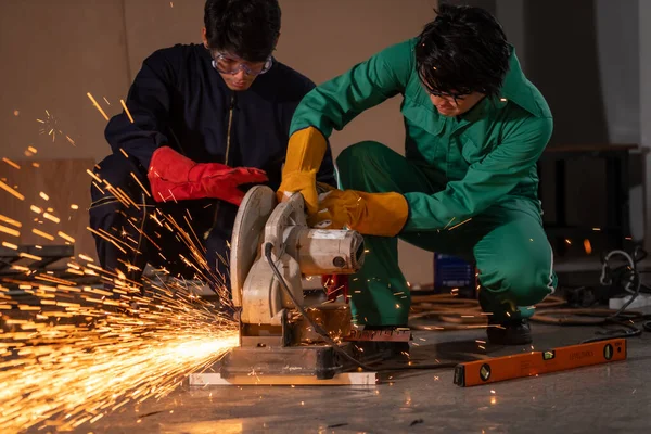 Professional mechanic man is cutting steel metal with rotating carbon blade cutter. Steel industry and workshop concept.