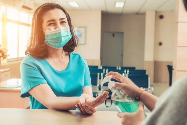 Receptionist and guest wearing face mask at front desk while having conversation in office or hospital . Covid 19 and coronavirus infection protection and protective policy concept .