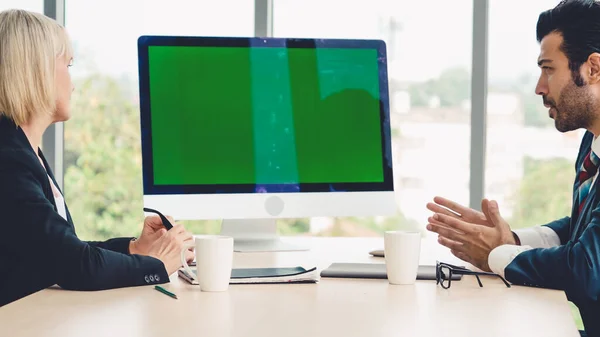 Business people in the conference room with green screen chroma key TV or computer on the office table. Diverse group of businessman and businesswoman in meeting on video conference call .