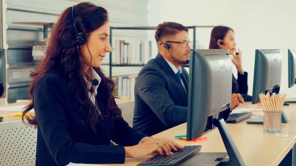 Ofiste çalışan kulaklık takan işadamları uzak müşteri ya da meslektaşlarını desteklemek için çalışıyorlar. Arama merkezi, tele pazarlama, müşteri destek acentesi telefon görüşmesinde hizmet sunar.