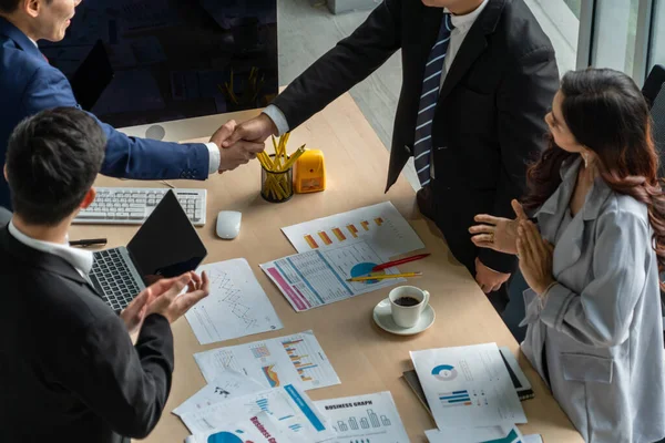 Grup iş adamları toplantı masasında el sıkışırken üst açıdan kendilerine güvenirler. Genç işadamı ve işkadını işçiler yatırım anlaşması imzaladılar.