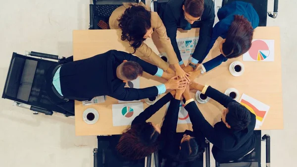 Happy business people celebrate teamwork success together with joy at office table shot from top view . Young businessman and businesswoman workers express cheerful victory showing unity and support .