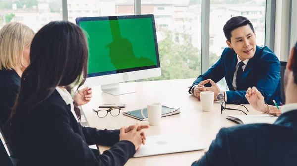 Business people in the conference room with green screen chroma key TV or computer on the office table. Diverse group of businessman and businesswoman in meeting on video conference call .