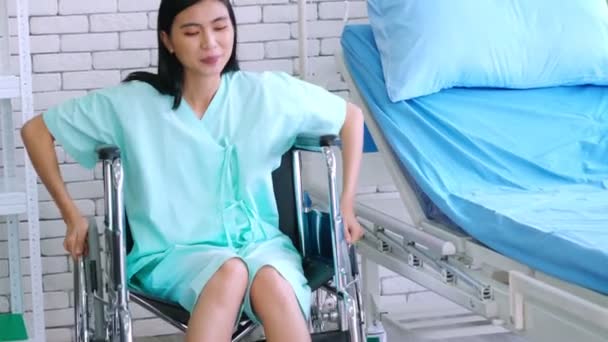 Fiatal, boldog ázsiai nő tolószékben egy kórházi kórteremben — Stock videók