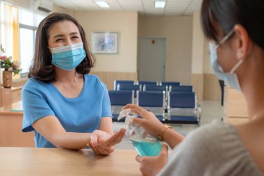 Ofiste ya da hastanede konuşurken resepsiyonist ve misafir maske takıyor. Covid 19 ve Coronavirus enfeksiyon koruması ve koruma politikası kavramı .