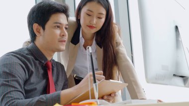 İki iş adamı toplantı odasında proje stratejisi hakkında konuşuyor. İş adamı, mali veri raporu hakkında sohbet ve tavsiyelerde bulunurken, modern işyerindeki iş arkadaşıyla proje planlamasını tartıştı.