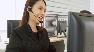 Ofiste çalışan kulaklık takan işadamları uzak müşteri ya da meslektaşlarını desteklemek için çalışıyorlar. Arama merkezi, tele pazarlama, müşteri destek acentesi telefon görüşmesinde hizmet sunar.