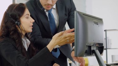 Ofiste çalışan kulaklık takan işadamları uzak müşteri ya da meslektaşlarını desteklemek için çalışıyorlar. Arama merkezi, tele pazarlama, müşteri destek acentesi telefon görüşmesinde hizmet sunar.