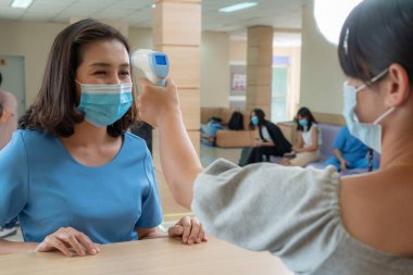 Ofiste ya da hastanede konuşurken resepsiyonist ve misafir maske takıyor. Covid 19 ve Coronavirus enfeksiyon koruması ve koruma politikası kavramı .