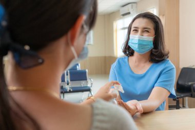 Ofiste ya da hastanede konuşurken resepsiyonist ve misafir maske takıyor. Covid 19 ve Coronavirus enfeksiyon koruması ve koruma politikası kavramı .