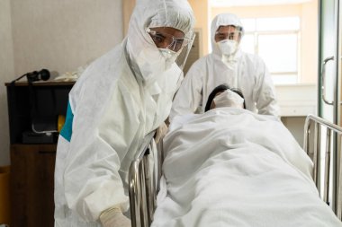 Acil servis doktoru ve doktor hastayı hastanedeki acil servise götürüyor. Doktor koronavirüs ve covid 19 koruma ve karantina kavramında koruyucu giysi ve yüz maskesi takıyor. .
