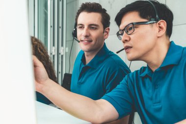 Ofiste çalışan kulaklık takan işadamları uzak müşteri ya da meslektaşlarını desteklemek için çalışıyorlar. Arama merkezi, tele pazarlama, müşteri destek acentesi telefon görüşmesinde hizmet sunar.