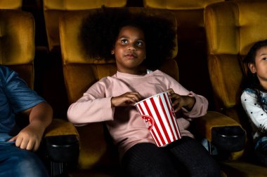 Üç çocuk eğleniyor ve sinemada film izlemekten zevk alıyor.