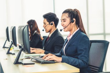 Ofiste çalışan kulaklık takan işadamları uzak müşteri ya da meslektaşlarını desteklemek için çalışıyorlar. Arama merkezi, tele pazarlama, müşteri destek acentesi telefon görüşmesinde hizmet sunar.