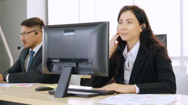 Ofiste çalışan kulaklık takan işadamları uzak müşteri ya da meslektaşlarını desteklemek için çalışıyorlar. Arama merkezi, tele pazarlama, müşteri destek acentesi telefon görüşmesinde hizmet sunar.