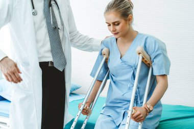 Doktor hastanede koltuk değnekli hastayla ilgileniyor. Fizyoterapist ve bacak yaralanması konsepti.