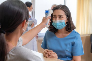 Ofiste ya da hastanede konuşurken resepsiyonist ve misafir maske takıyor. Covid 19 ve Coronavirus enfeksiyon koruması ve koruma politikası kavramı .