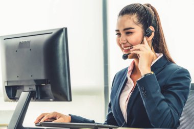 Ofiste çalışan kulaklık takan işadamları uzak müşteri ya da meslektaşlarını desteklemek için çalışıyorlar. Arama merkezi, tele pazarlama, müşteri destek acentesi telefon görüşmesinde hizmet sunar.