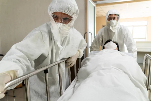 위생국과 의사가 응급실로 환자를 옮기고 닥터는 코로나 바이러스의 개념에서 보호용 — 스톡 사진