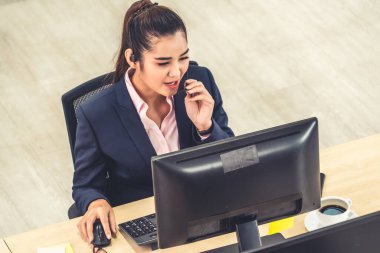 Ofiste çalışan kulaklık takan işadamları uzak müşteri ya da meslektaşlarını desteklemek için çalışıyorlar. Arama merkezi, tele pazarlama, müşteri destek acentesi telefon görüşmesinde hizmet sunar.