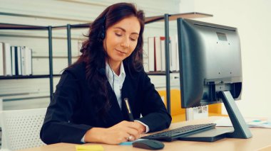 Ofiste çalışan kulaklık takan işadamları uzak müşteri ya da meslektaşlarını desteklemek için çalışıyorlar. Arama merkezi, tele pazarlama, müşteri destek acentesi telefon görüşmesinde hizmet sunar.