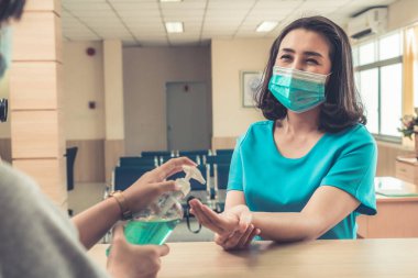 Ofiste ya da hastanede konuşurken resepsiyonist ve misafir maske takıyor. Covid 19 ve Coronavirus enfeksiyon koruması ve koruma politikası kavramı .