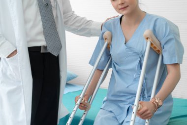 Doktor hastanede koltuk değnekli hastayla ilgileniyor. Fizyoterapist ve bacak yaralanması konsepti.