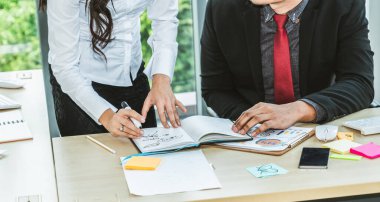 İki iş adamı toplantı odasında proje stratejisi hakkında konuşuyor. İş adamı, mali veri raporu hakkında sohbet ve tavsiyelerde bulunurken, modern işyerindeki iş arkadaşıyla proje planlamasını tartıştı.