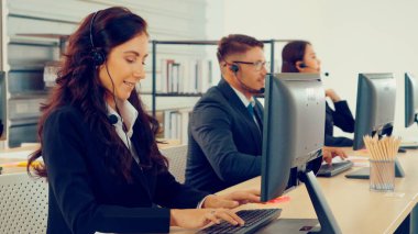 Ofiste çalışan kulaklık takan işadamları uzak müşteri ya da meslektaşlarını desteklemek için çalışıyorlar. Arama merkezi, tele pazarlama, müşteri destek acentesi telefon görüşmesinde hizmet sunar.