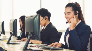 Ofiste çalışan kulaklık takan işadamları uzak müşteri ya da meslektaşlarını desteklemek için çalışıyorlar. Arama merkezi, tele pazarlama, müşteri destek acentesi telefon görüşmesinde hizmet sunar.