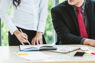 İki iş adamı toplantı odasında proje stratejisi hakkında konuşuyor. İş adamı, mali veri raporu hakkında sohbet ve tavsiyelerde bulunurken, modern işyerindeki iş arkadaşıyla proje planlamasını tartıştı.