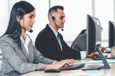 Ofiste çalışan kulaklık takan işadamları uzak müşteri ya da meslektaşlarını desteklemek için çalışıyorlar. Arama merkezi, tele pazarlama, müşteri destek acentesi telefon görüşmesinde hizmet sunar.