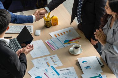 Grup iş adamları toplantı masasında el sıkışırken üst açıdan kendilerine güvenirler. Genç işadamı ve işkadını işçiler yatırım anlaşması imzaladılar.