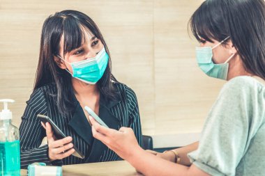 Ofiste ya da hastanede konuşurken resepsiyonist ve misafir maske takıyor. Covid 19 ve Coronavirus enfeksiyon koruması ve koruma politikası kavramı .