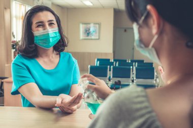 Ofiste ya da hastanede konuşurken resepsiyonist ve misafir maske takıyor. Covid 19 ve Coronavirus enfeksiyon koruması ve koruma politikası kavramı .
