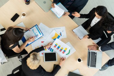 İş adamları grup toplantısı ofiste yukarıdan çekildi. İş kadınları, iş adamları ve ofis çalışanları, proje planlama belgeleriyle takım konferansında toplantı masasında çalışıyorlar. .