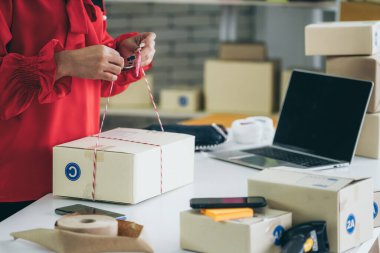 Çevrimiçi satıcı ev ofisinde çalışıyor ve teslimat kutusunu müşteriye paketliyor. İnternette e-ticaret yapan küçük işletme sahibi ya da girişimci.