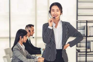 Ofiste çalışan kulaklık takan işadamları uzak müşteri ya da meslektaşlarını desteklemek için çalışıyorlar. Arama merkezi, tele pazarlama, müşteri destek acentesi telefon görüşmesinde hizmet sunar.