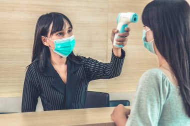 Ofiste ya da hastanede konuşurken resepsiyonist ve misafir maske takıyor. Covid 19 ve Coronavirus enfeksiyon koruması ve koruma politikası kavramı .