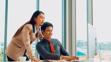 İki iş adamı toplantı odasında proje stratejisi hakkında konuşuyor. İş adamı, mali veri raporu hakkında sohbet ve tavsiyelerde bulunurken, modern işyerindeki iş arkadaşıyla proje planlamasını tartıştı.