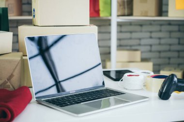 Nakliye kutusunun arka planında boş ekranı olan dizüstü bilgisayar. Çevrimiçi perakende satış mağazası, teslimat siparişi ve müşteri hizmetleri kavramı.