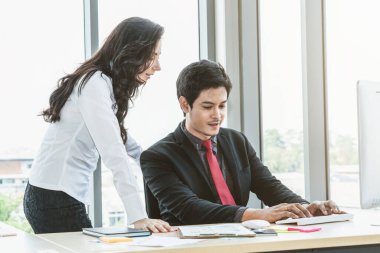 İki iş adamı toplantı odasında proje stratejisi hakkında konuşuyor. İş adamı, mali veri raporu hakkında sohbet ve tavsiyelerde bulunurken, modern işyerindeki iş arkadaşıyla proje planlamasını tartıştı.