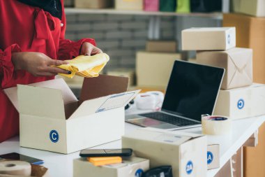 Çevrimiçi satıcı ev ofisinde çalışıyor ve teslimat kutusunu müşteriye paketliyor. İnternette e-ticaret yapan küçük işletme sahibi ya da girişimci.