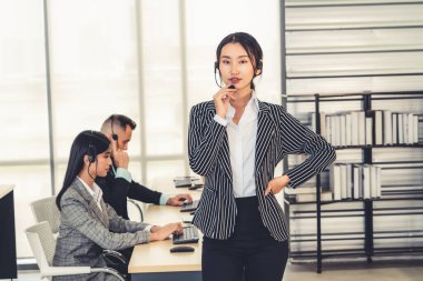 Ofiste çalışan kulaklık takan işadamları uzak müşteri ya da meslektaşlarını desteklemek için çalışıyorlar. Arama merkezi, tele pazarlama, müşteri destek acentesi telefon görüşmesinde hizmet sunar.
