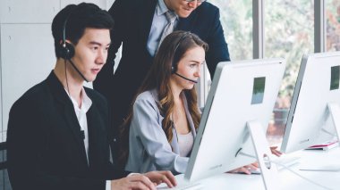 Ofiste çalışan kulaklık takan işadamları uzak müşteri ya da meslektaşlarını desteklemek için çalışıyorlar. Arama merkezi, tele pazarlama, müşteri destek acentesi telefon görüşmesinde hizmet sunar.